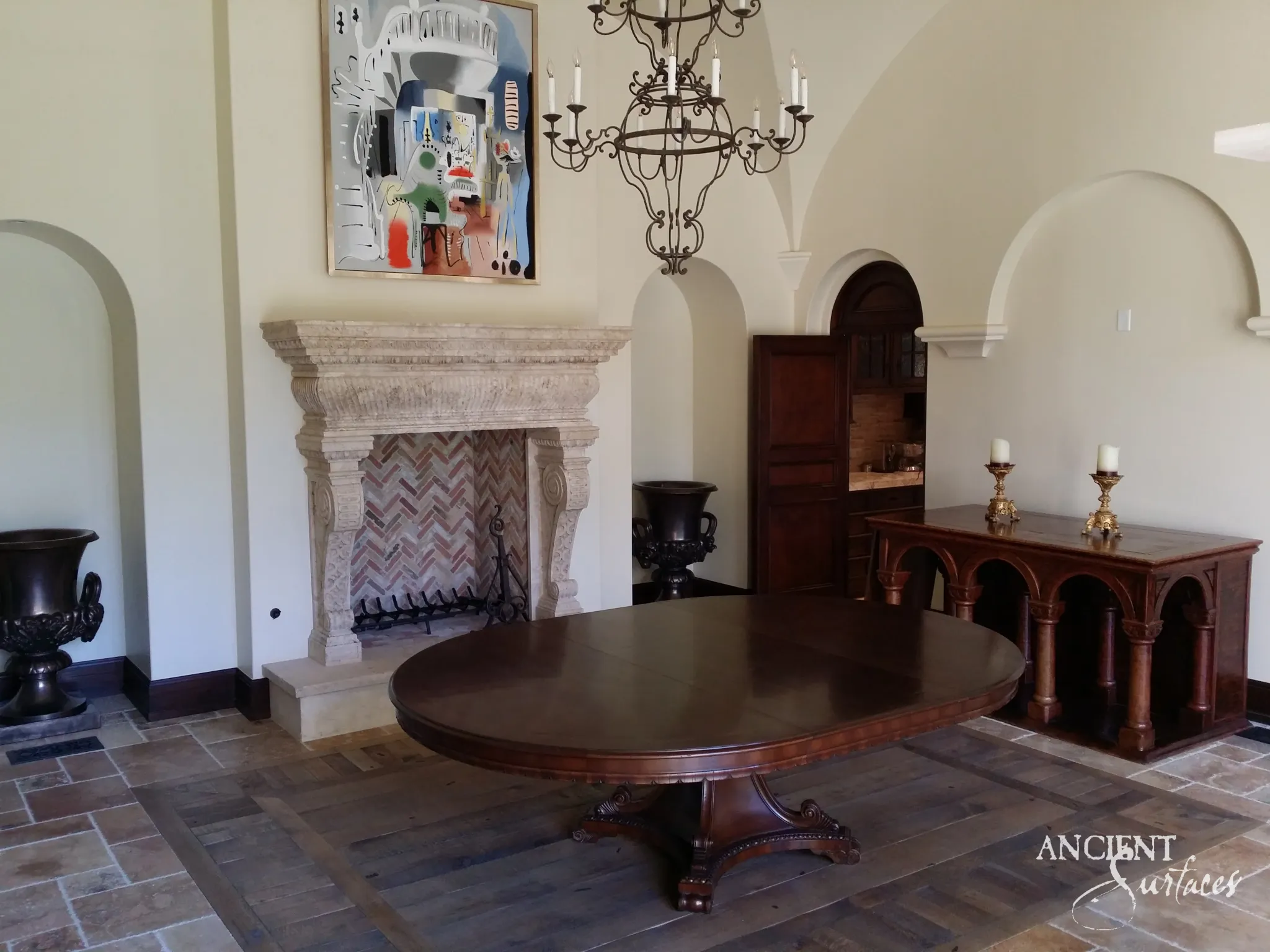 Rustic reclaimed limestone fireplace of tumbled blocks with an arched opening in an arcaded plaster room