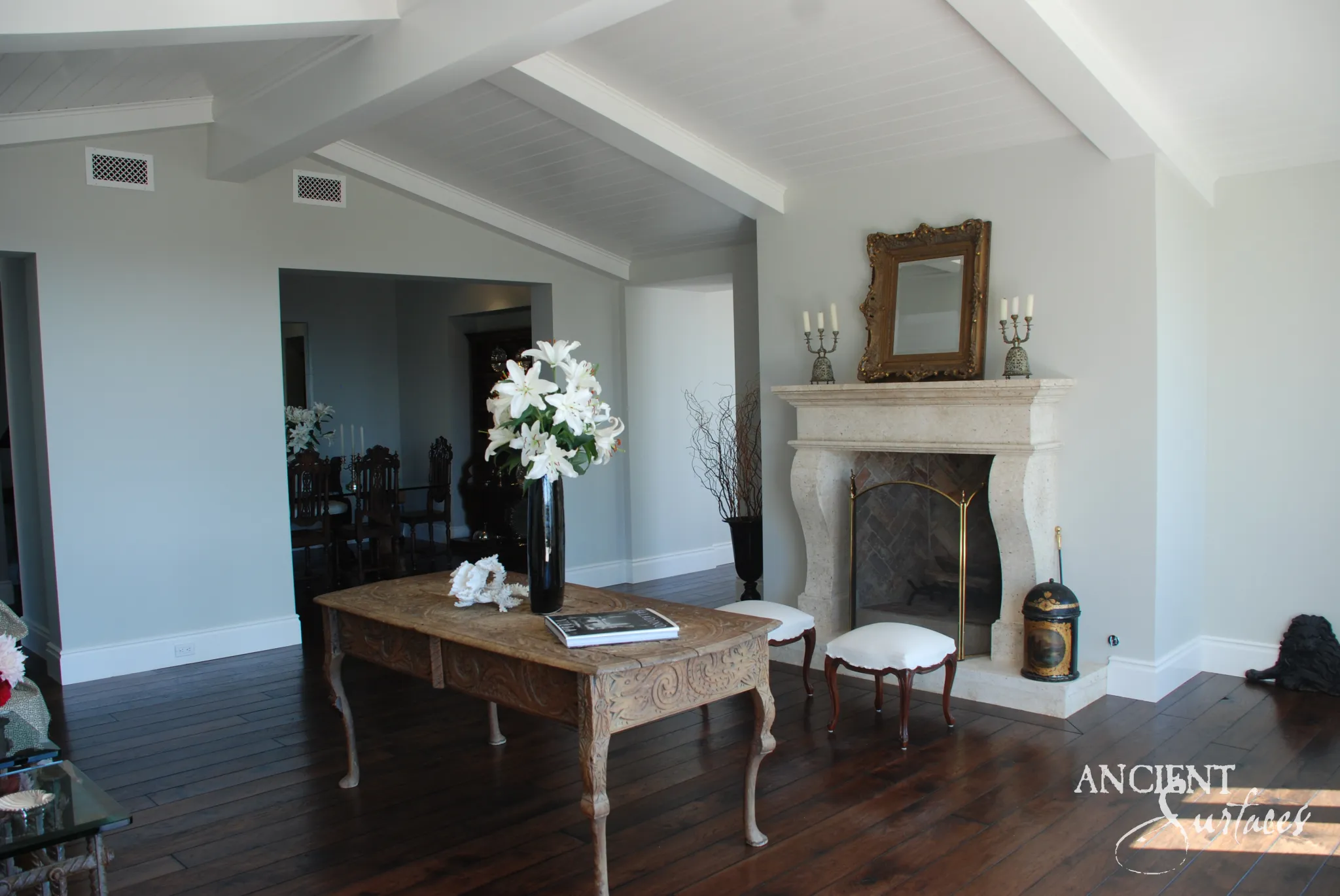 French provincial reclaimed limestone fireplace mantel from Ancient Surfaces with scrolled jambs in a bright beamed living room