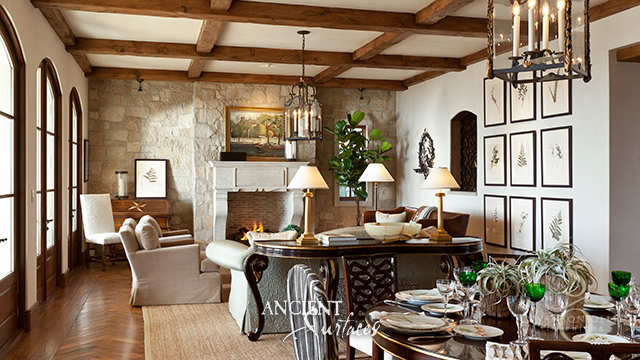 Reclaimed antique limestone fireplace surround from Ancient Surfaces set in a stone chimney breast beneath a coffered timber ceiling