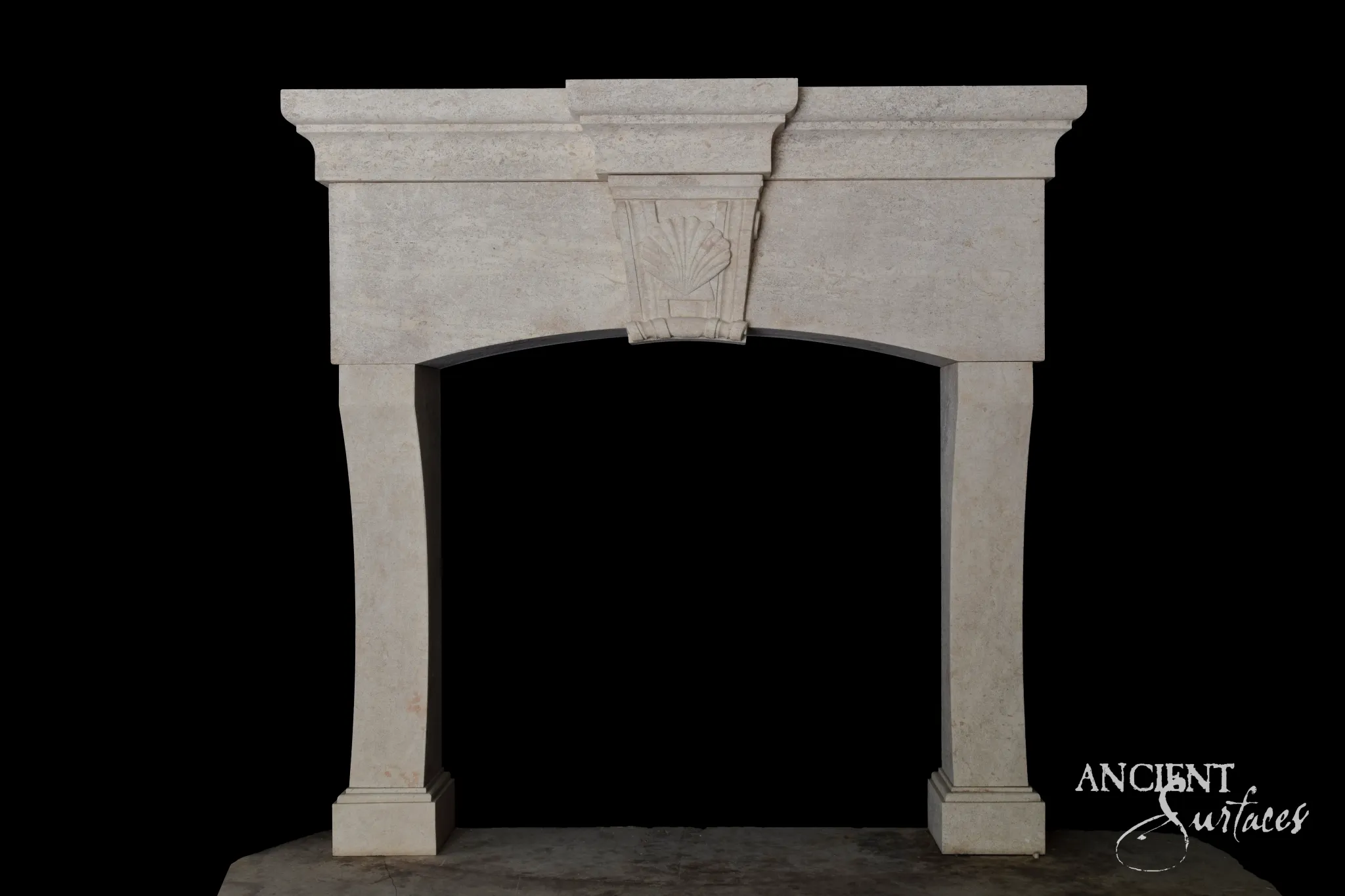 Reclaimed antique limestone fireplace mantel from Ancient Surfaces with a stepped cornice and carved keystone above an arched opening