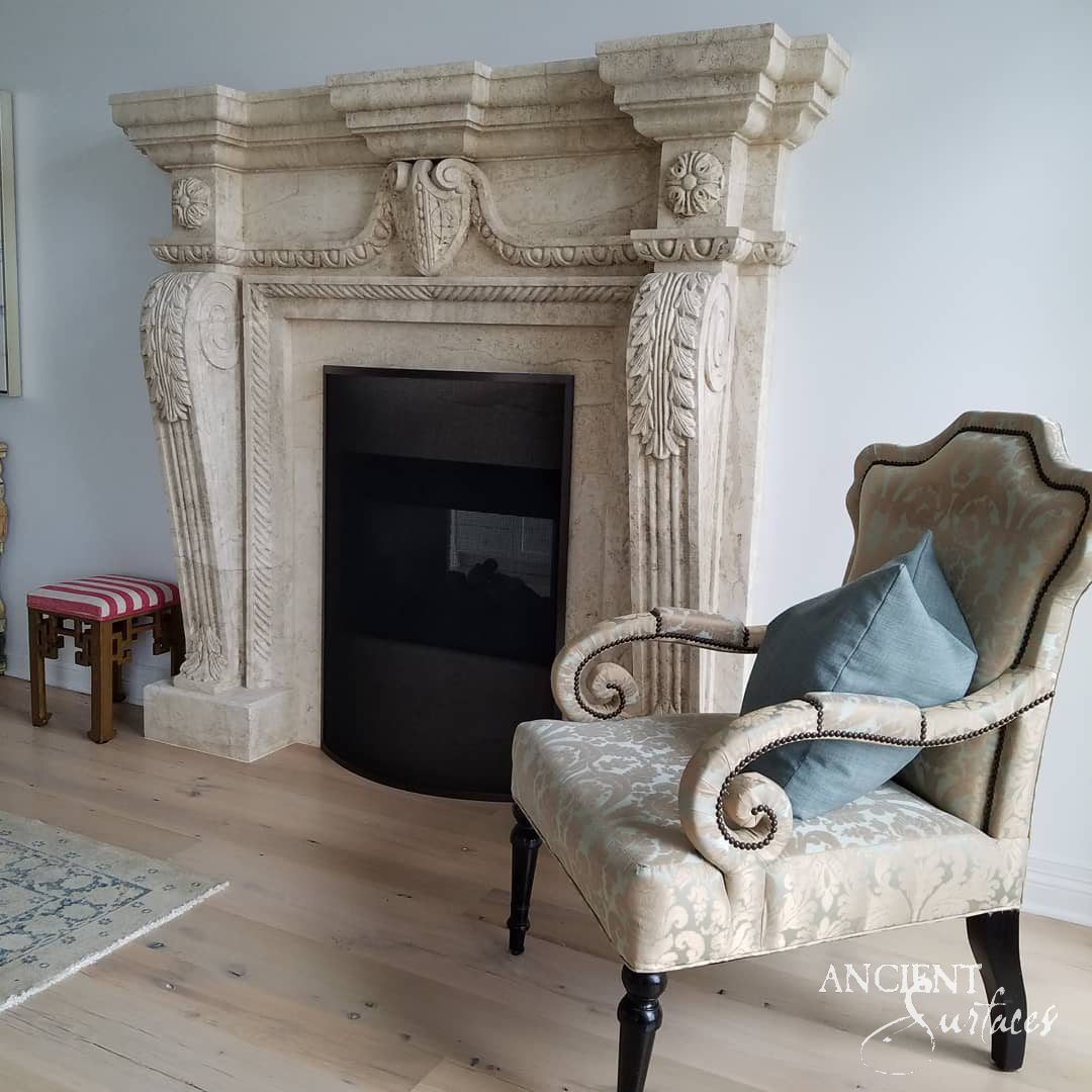Grand reclaimed limestone fireplace mantel from Ancient Surfaces with winged acanthus corbels and a carved shield frieze