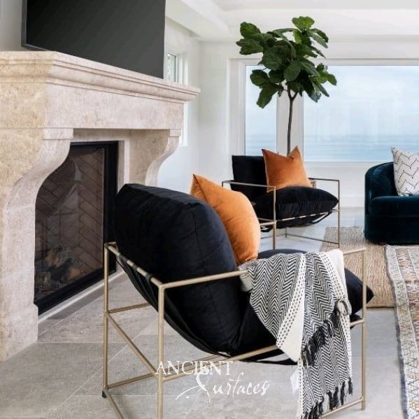 Clean lined reclaimed limestone fireplace mantel from Ancient Surfaces with an arched firebox in a modern living room