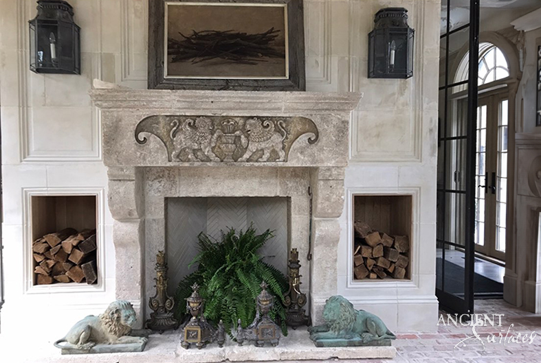 Weathered reclaimed antique limestone fireplace mantel from Ancient Surfaces with a deeply carved foliate cartouche in a panelled hall