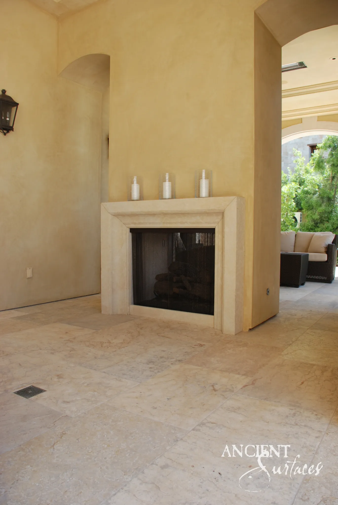Ancient Surfaces reclaimed limestone fireplace mantel installed in an ochre plastered outdoor loggia